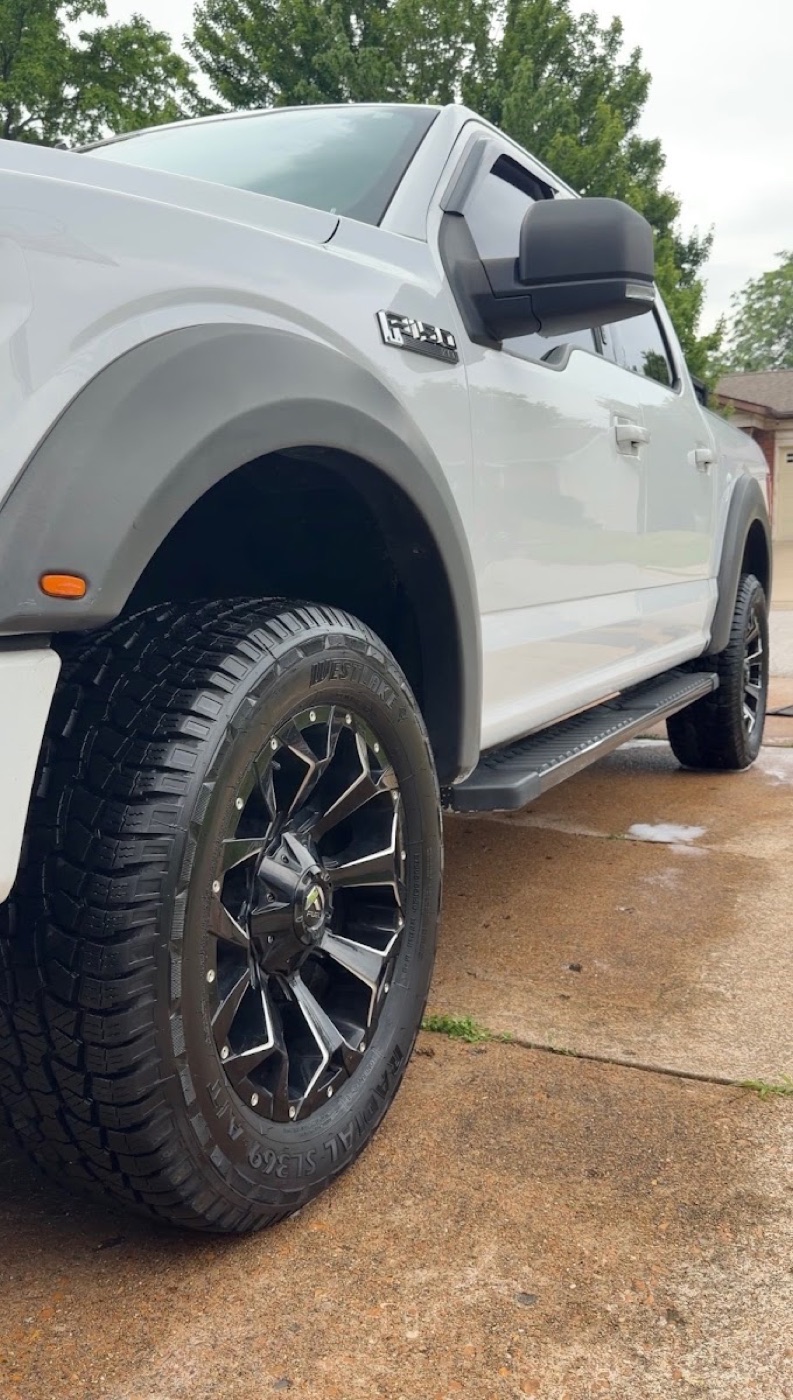 Gleaming white truck exterior and clean wheel after a wash, still wet with soap